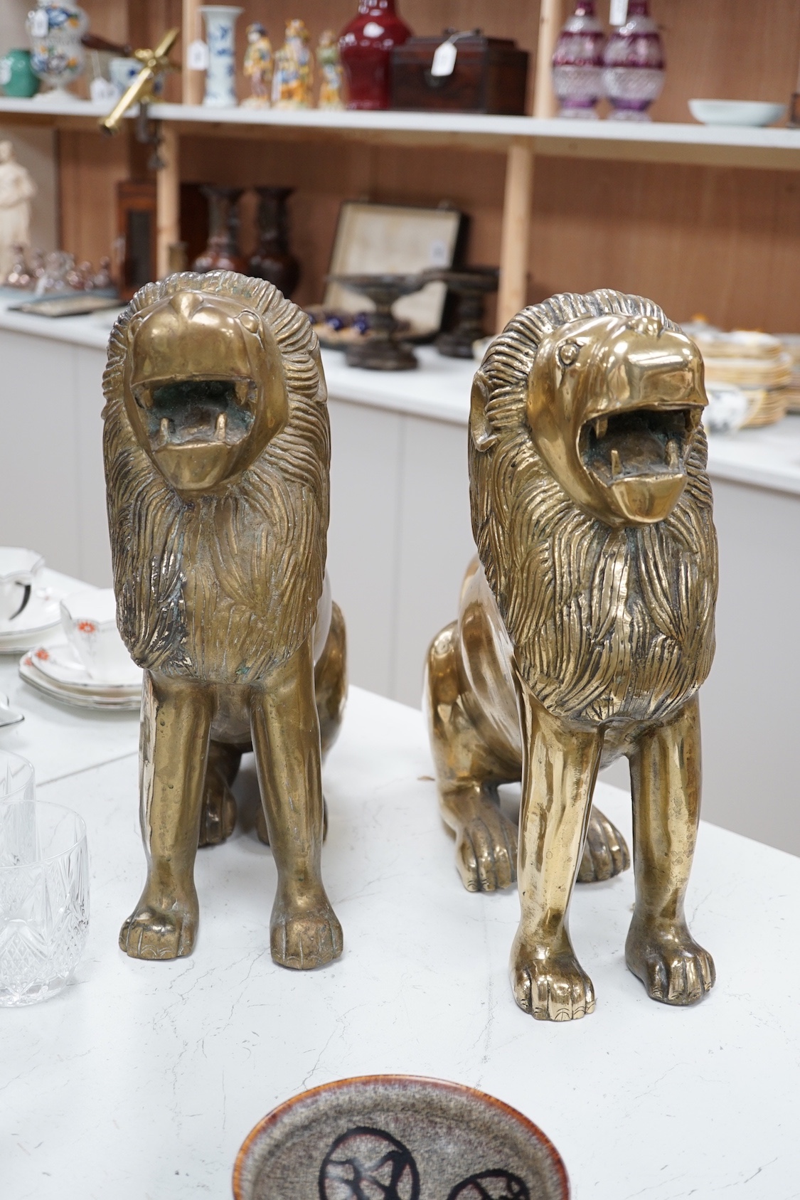 A pair of large brass lion models. 39cm